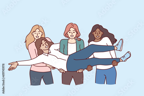 Multiethnic women students raise classmate in arms to congratulate on educational achievements and take memorable photo. Cheerful multiethnic girls get pleasure from lack of disagreement.