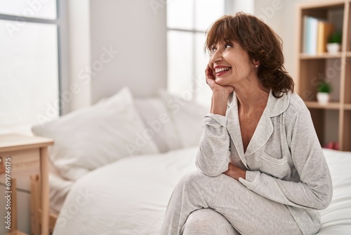 Middle age woman smiling confident sitting on bed at bedroom