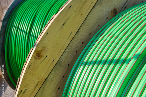 Wooden rolls of green colored industrial tube cable for underground fiber optic internet cabling.	