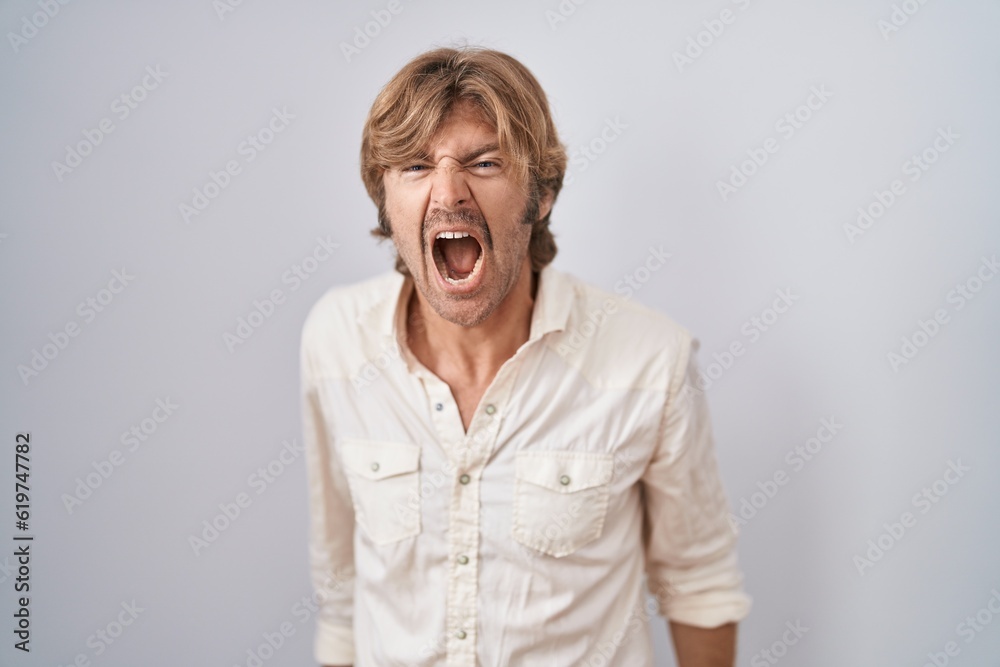 Middle age man standing over isolated background angry and mad screaming frustrated and furious, shouting with anger. rage and aggressive concept. Middle age man standing over isolated background angry and mad screaming frustrated and furious, shouting with anger. rage and aggressive concept.