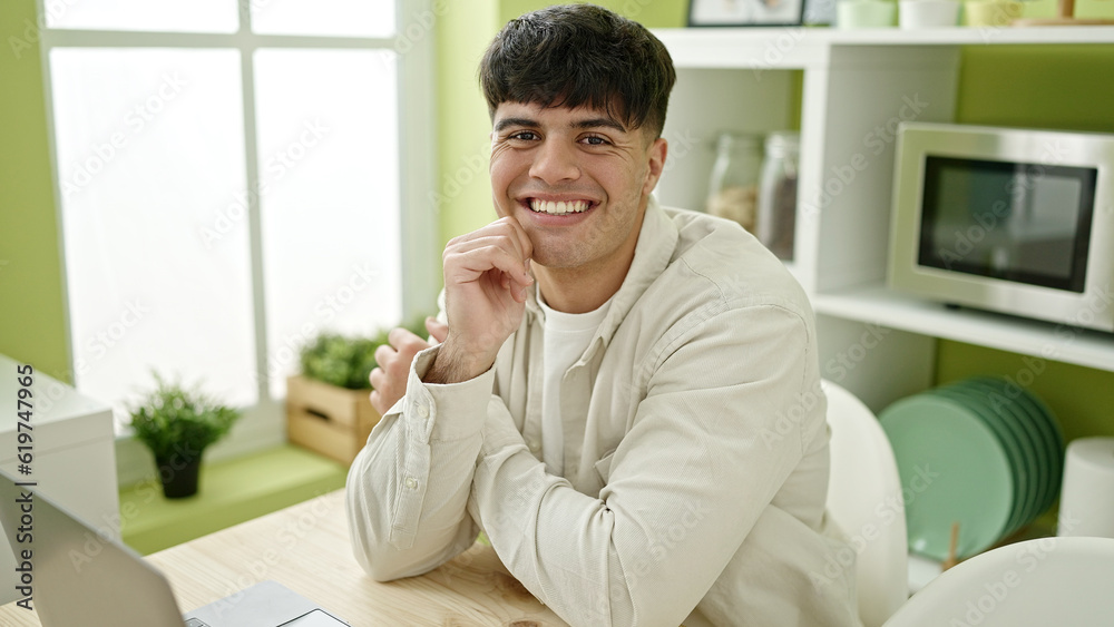 Young hispanic man smiling confident using laptop at dinning room