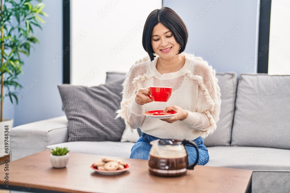 Young chinese woman having breakfast sitting on sofa at home Young chinese woman having breakfast sitting on sofa at home