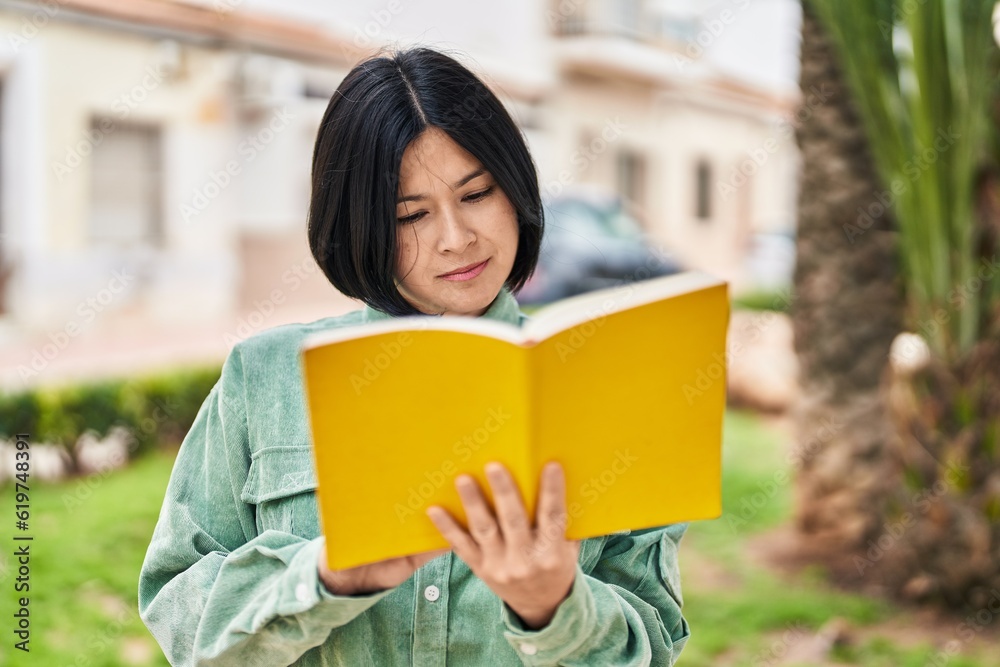 Young chinese woman reading book with relaxed expression at park Young chinese woman reading book with relaxed expression at park