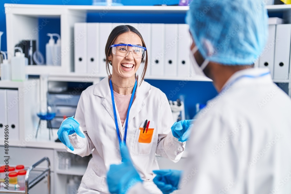 Man and woman scientists smiling confident speaking at laboratory