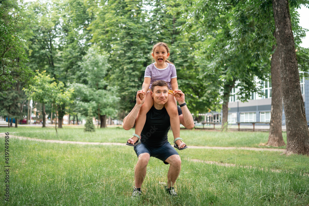 Fototapeta premium father doing squats with child daughter on the shoulders. active workout with family, healthy parenting 