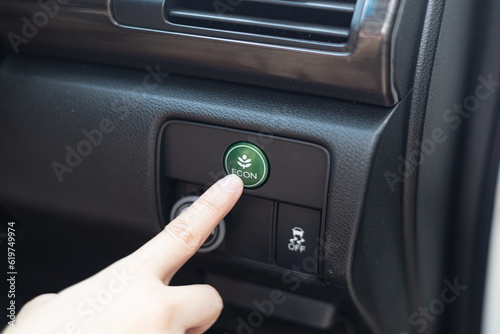 Close-up woman's hand is pressing the fuel economy  or ECO button for the vehicle's fuel economy. Energy-saving driving mode. Energy saving concept. Green eco drive. eco mode to save the environment.
