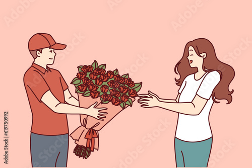 Flower delivery man hands bouquet to woman delighted with unexpected valentine day gift from boyfriend. Courier hands bouquet of red roses to happy client, to advertise services of flower shop