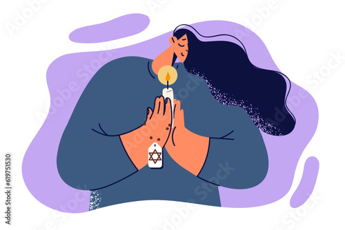 Praying jewish woman holds candle and amulet with star of david, performing religious ritual