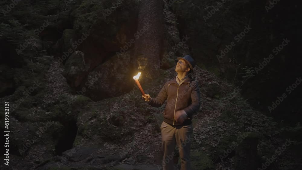 Male Adventurer Exploring Stone Rock Cave in Darkness Outside Using Torch Light Male Adventurer Exploring Stone Rock Cave in Darkness Outside Using Torch Light