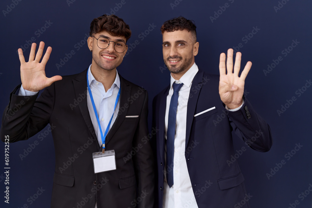 Two hispanic business men wearing business clothes showing and pointing up with fingers number nine while smiling confident and happy. Two hispanic business men wearing business clothes showing and pointing up with fingers number nine while smiling confident and happy.
