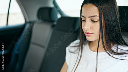 Young beautiful hispanic woman passenger sitting on car with relaxed expression at street