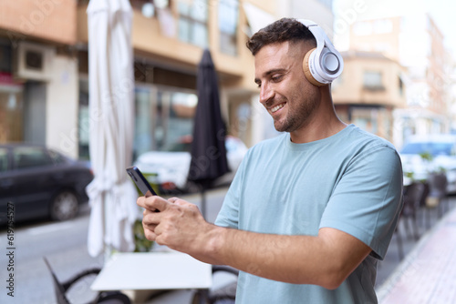 Young hispanic man listening to music at coffee shop terrace