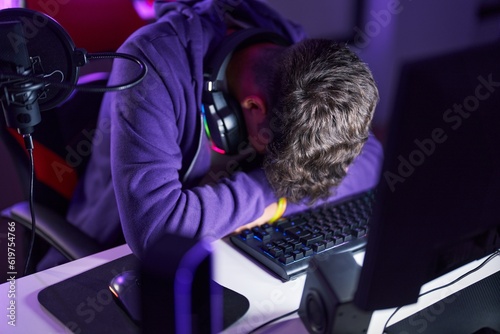 Young hispanic teenager streamer stressed using computer at gaming room