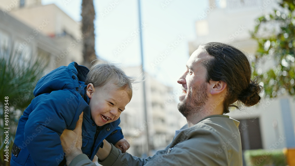 Father and son smiling confident hugging each other at park