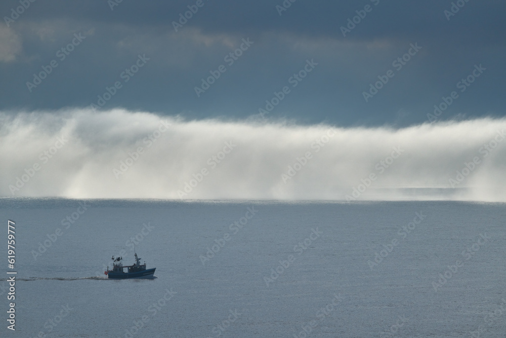 A bank of fog on the sea with a boat in the foreground