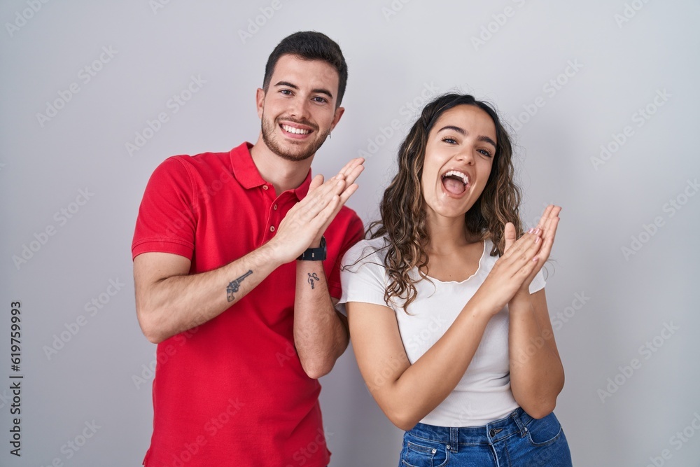 Young hispanic couple standing over isolated background clapping and applauding happy and joyful, smiling proud hands together Young hispanic couple standing over isolated background clapping and applauding happy and joyful, smiling proud hands together