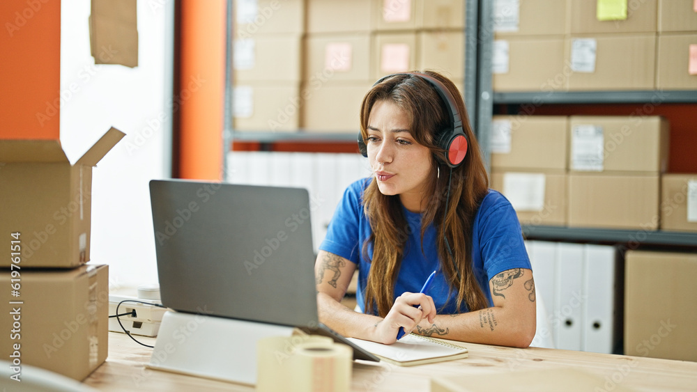 Young beautiful hispanic woman ecommerce business agent on a video call writing on package at office Young beautiful hispanic woman ecommerce business agent on a video call writing on package at office