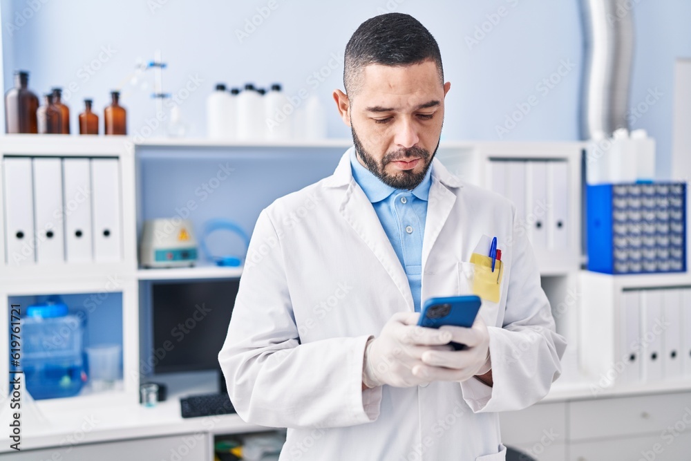 Young latin man scientist using smartphone at laboratory Young latin man scientist using smartphone at laboratory