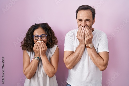Принти на полотні Middle age hispanic couple together over pink background laughing and embarrasse