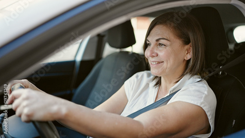 Middle age hispanic woman smiling confident driving car at street