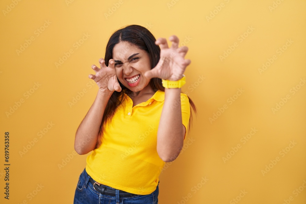 Young arab woman standing over yellow background smiling funny doing claw gesture as cat, aggressive and sexy expression Young arab woman standing over yellow background smiling funny doing claw gesture as cat, aggressive and sexy expression