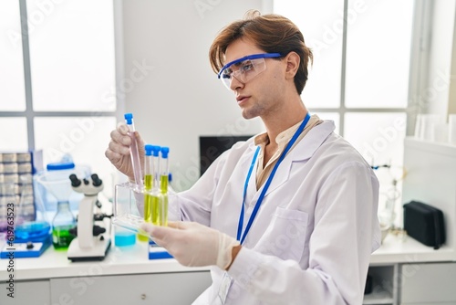 Young caucasian man scientist holding test tubes at laboratory