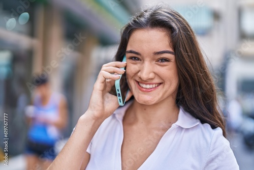 Young hispanic woman smiling confident talking on smartphone at street