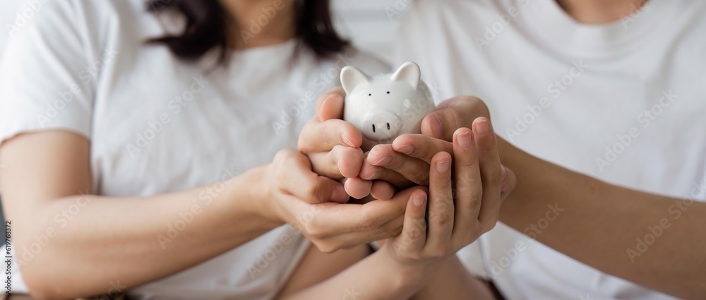 Happy asian young couple love calculate and putting coin in piggy bank for saving money to buy real estate for new home. Business finance, deposit with banking for financial planning future together