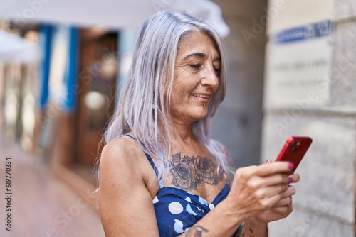 Middle age grey-haired woman smiling confident using smartphone at street