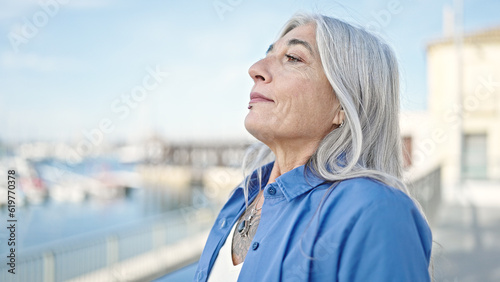 Middle age grey-haired woman breathing at seaside