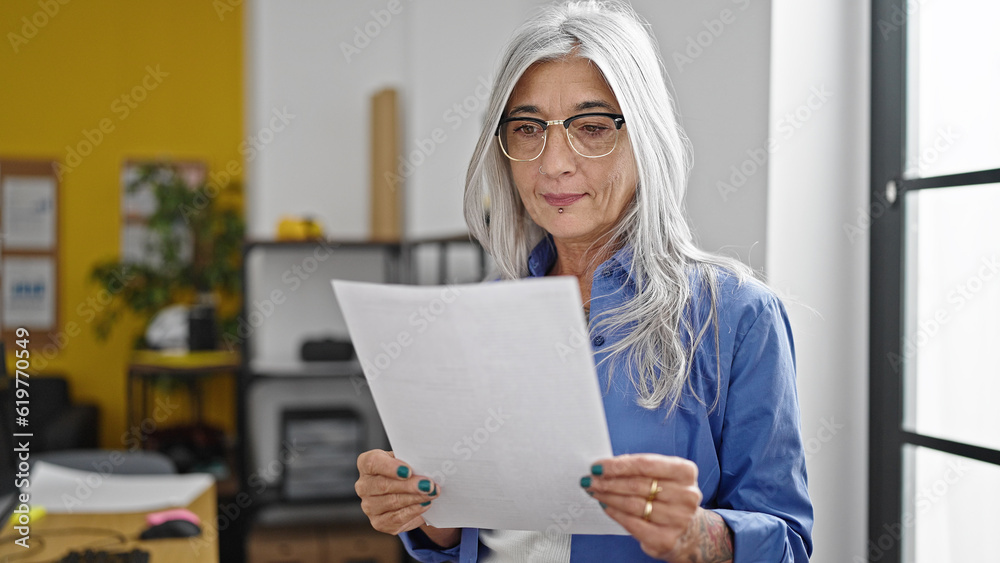Middle age grey-haired woman business worker reading document at office Middle age grey-haired woman business worker reading document at office
