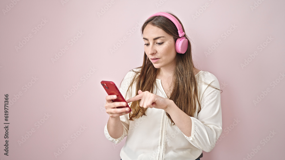 Young beautiful hispanic woman using smartphone wearing headphones over isolated pink background Young beautiful hispanic woman using smartphone wearing headphones over isolated pink background