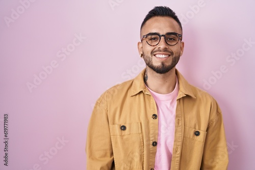 Young hispanic man standing over pink background with a happy and cool smile on face. lucky person. © Krakenimages.com