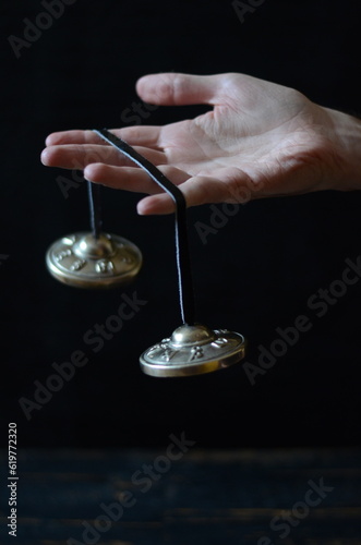 Tibetan tingsha (taal) cymbals on the hand - music instruments for meditation, relaxation, yoga on the black background