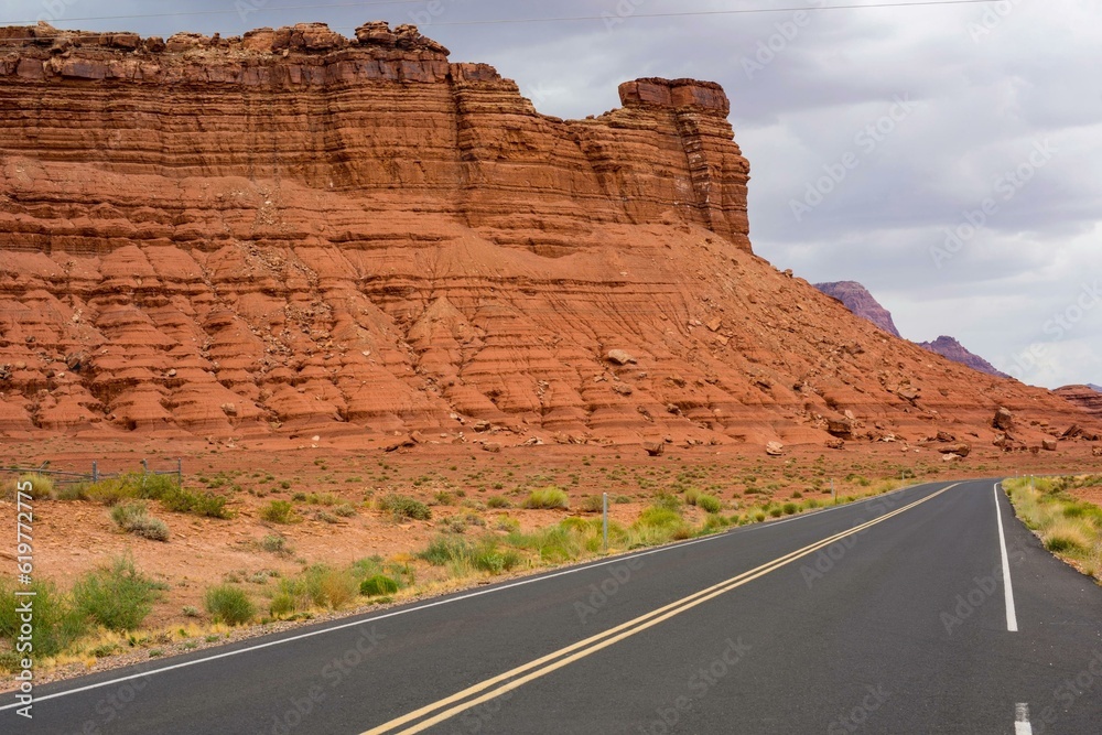 Solitude in the Desert: Solo Driving on Dark Black Road, Amidst Red Rocks and Majestic Mountains Solitude in the Desert: Solo Driving on Dark Black Road, Amidst Red Rocks and Majestic Mountains