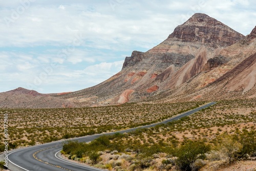 Solitude in the Desert: Solo Driving on Dark Black Road, Amidst Red Rocks and Majestic Mountains