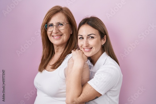 Hispanic mother and daughter wearing casual white t shirt smiling with a happy and cool smile on face. showing teeth.