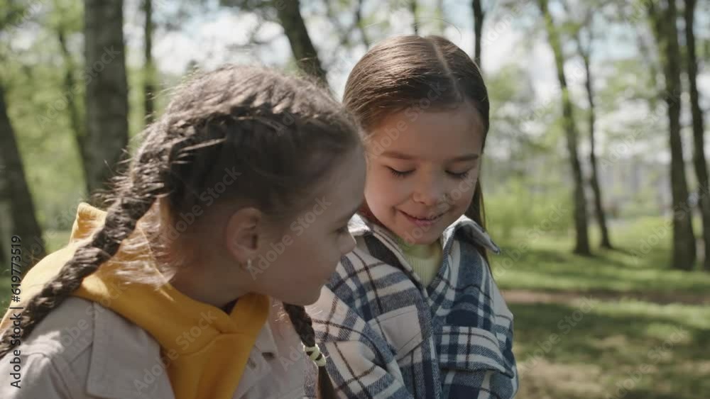 Medium close up shot of two cute little girls sitting in park and summer day and chattingMedium close up shot of two cute little girls sitting in park and summer day and chatting Medium close up shot of two cute little girls sitting in park and summer day and chattingMedium close up shot of two cute little girls sitting in park and summer day and chatting