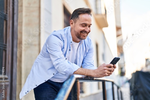 Young caucasian man smiling confident using smartphone at street