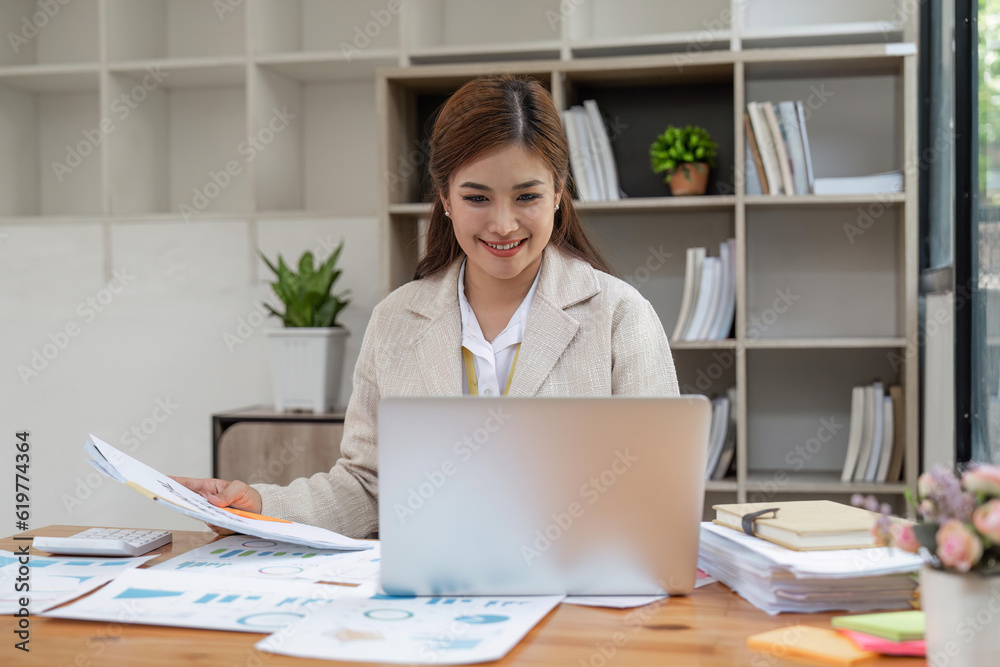 Successful smiling mature businesswoman using laptop and computer while doing some paperwork at the office Successful smiling mature businesswoman using laptop and computer while doing some paperwork at the office