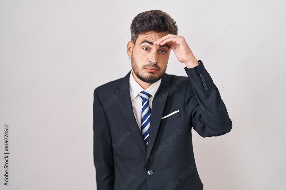 Young hispanic man with tattoos wearing business suit and tie worried and stressed about a problem with hand on forehead, nervous and anxious for crisis Young hispanic man with tattoos wearing business suit and tie worried and stressed about a problem with hand on forehead, nervous and anxious for crisis