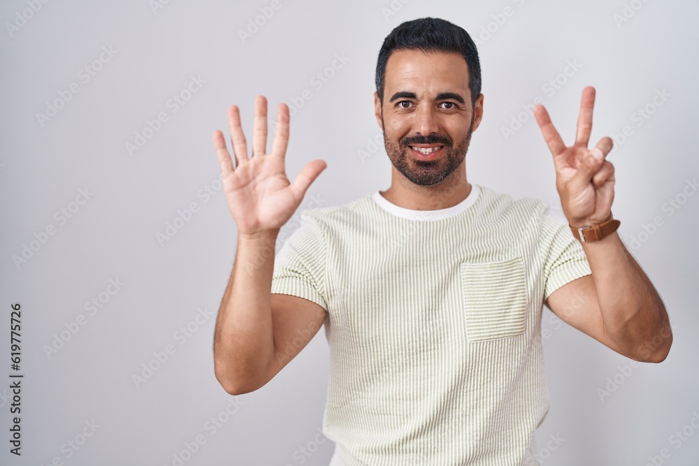 Hispanic man with beard standing over isolated background showing and pointing up with fingers number seven while smiling confident and happy. Hispanic man with beard standing over isolated background showing and pointing up with fingers number seven while smiling confident and happy.