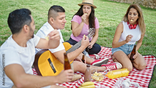Group of people having picnic sitting on grass at park