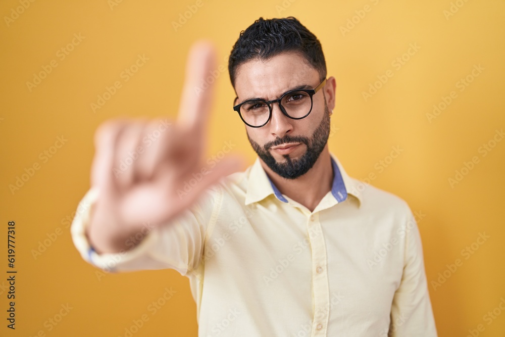 Hispanic young man wearing business clothes and glasses pointing with finger up and angry expression, showing no gesture