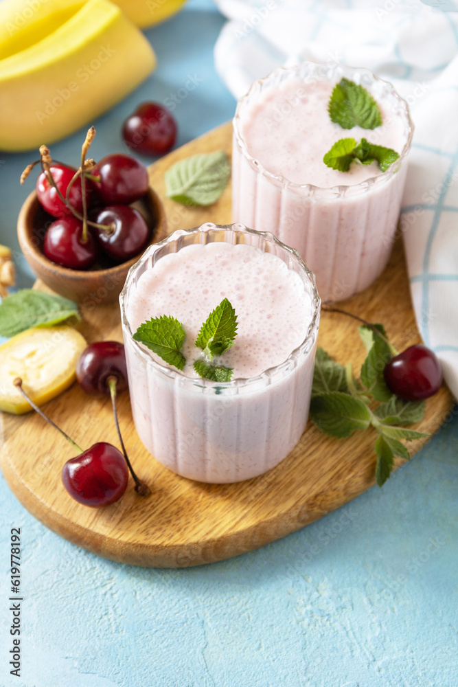 Fresh seasonal smoothies. Smoothies with sweet cherry and banana with yogurt on wooden board on a stone background. Copy space. Fresh seasonal smoothies. Smoothies with sweet cherry and banana with yogurt on wooden board on a stone background. Copy space.