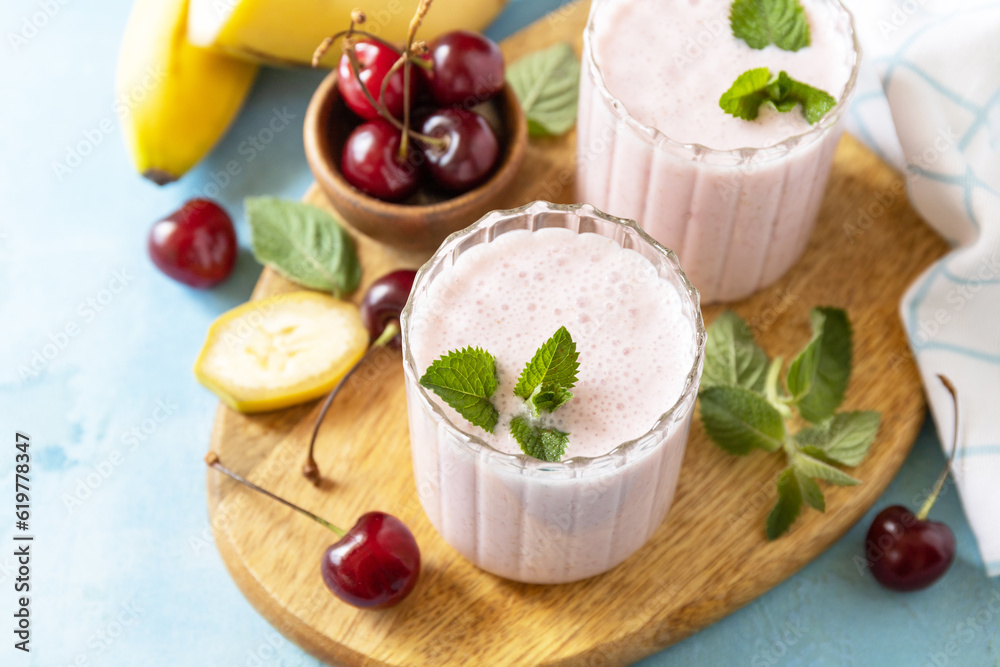 Smoothies with sweet cherry and banana with yogurt on wooden board on a stone background. Fresh seasonal smoothies. Copy space. Smoothies with sweet cherry and banana with yogurt on wooden board on a stone background. Fresh seasonal smoothies. Copy space.