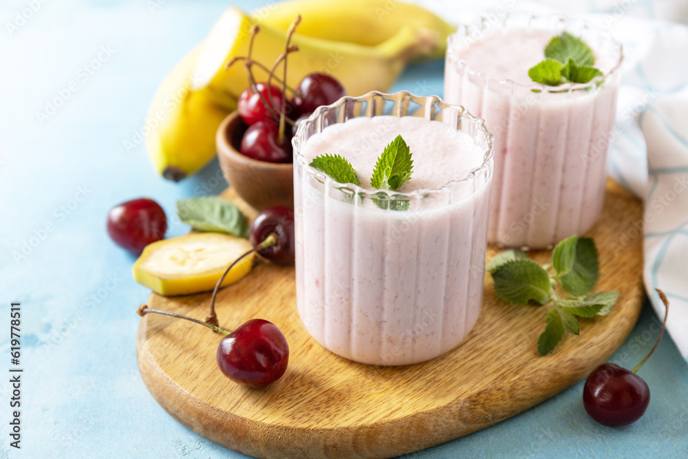 Fresh seasonal smoothies. Smoothies with sweet cherry and banana with yogurt on wooden board on a stone background. Copy space. Fresh seasonal smoothies. Smoothies with sweet cherry and banana with yogurt on wooden board on a stone background. Copy space.