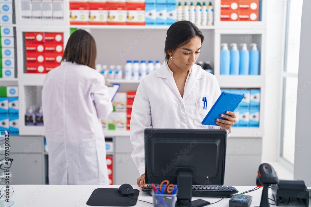 Two women pharmacist using touchpad working at pharmacy
