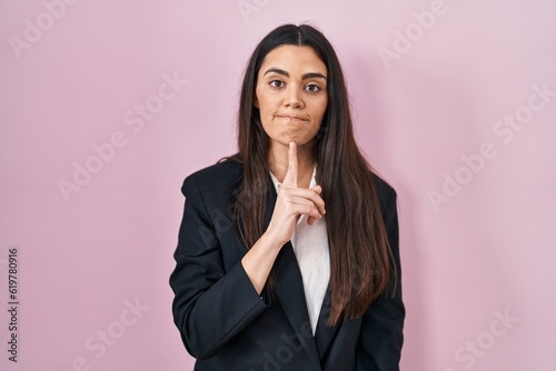 Young brunette woman wearing business style over pink background thinking concentrated about doubt with finger on chin and looking up wondering
