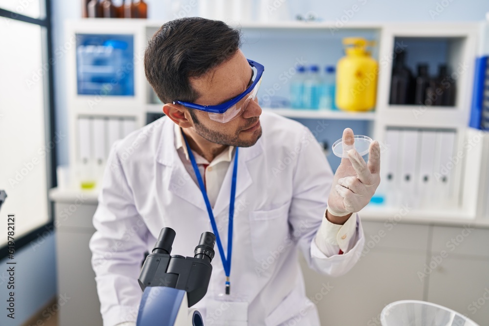 Young hispanic man scientist looking sample at laboratory Young hispanic man scientist looking sample at laboratory